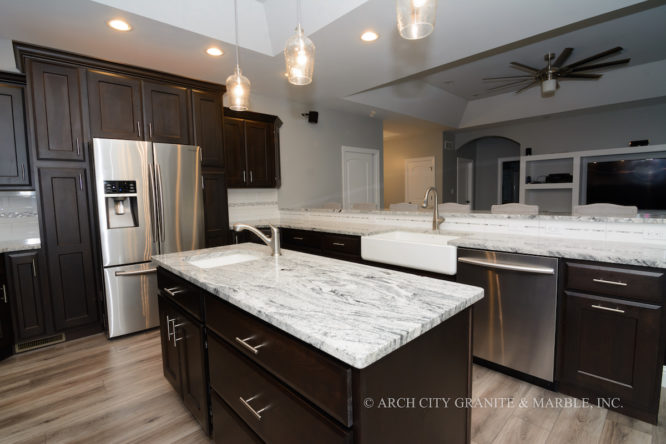 Contemporary kitchen with dark cabinets is paired with light granite countertops and white apron front sink in Union, MO